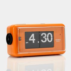 an orange alarm clock sitting on top of a table