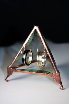 an unusual ring with two rings in it sitting on top of a triangle shaped object