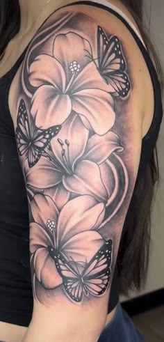 a woman's shoulder with butterflies and flowers on her arm, in black and white