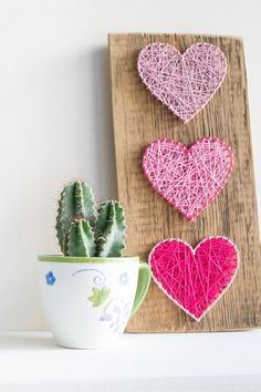 three heart shaped string art hanging on a wall next to a potted succulent