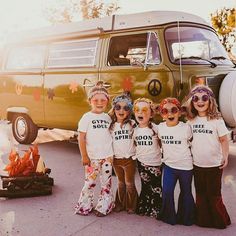 four girls wearing t - shirts with words on them standing in front of a camper van