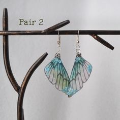 Wear a little Fairy magic to brighten up your day!  Pretty little fairy wings with tiny little blooms, the perfect ear accessory  These earrings are a mere 2  inches long with an extra inch for the silver earring finding, making these earrings dangle around 3" long.   Each fairy wing replica is handmade in a shimmery teal color and then finished in a coat of resin, Adorned with tiny little matching floral blooms. Comes in two variations to choose from. NO FAIRIES were harmed in the making of the Handmade Fairycore Dangle Earrings, Handmade Fairycore Drop Earrings, Handmade Dangle Earrings In Fairycore Style, Fantasy Winged Jewelry Gift, Green Fairy Earrings For Gift, Handmade Fairy Style Dangle Jewelry, Handmade Fairy Dangle Jewelry, Nickel-free Fairycore Earrings For Jewelry Making, Fairy Style Green Earrings For Gifts