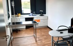 a kitchen with a table and chairs in front of a window that has a laptop on it