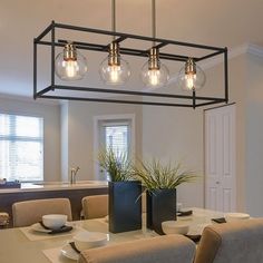 a dining room table and chairs with lights hanging over it in the middle of the room