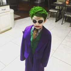 a young boy dressed as the joker in a living room with white tile flooring