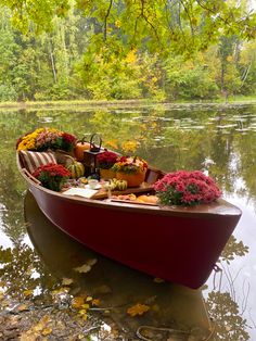 a red boat filled with lots of flowers floating on top of a body of water