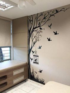 a bedroom with a tree painted on the wall and birds flying around in the air