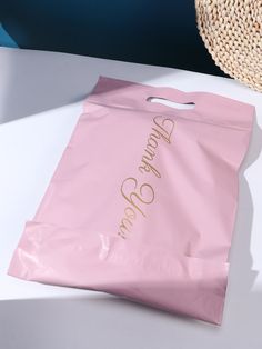 a pink shopping bag sitting on top of a white table next to a straw hat