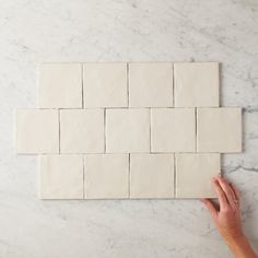 a hand is placing tiles on the wall