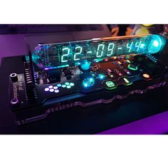 a clock made out of electronic components on a black surface with purple lighting around it