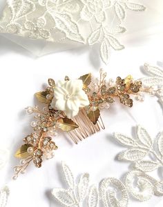 LOUISA is a beautiful handcrafted gold, crystal and pearl hair comb with a central porcelain flower. Graceful wired branches of glass pearls, rhinestones and gold leaves make this romantic hairpiece perfect for classic, elegant bridal styles and weddings! ☆ DETAILS ☆ - Designed with hand-wired branches of leaves, crystals and glass pearls. - Gold plated comb is sturdy and strong for a secure hold. - All elements are flexible for slight adjustments before being worn. - Length: About 12.5 cm (5 inches). - Width: About 5.5 cm (2.25 inches). - Heirloom quality for passing down through the years - Attention to detail and craftmanship - MADE TO ORDER: Please allow 2-4 weeks for creation, plus shipping times (Approximately 1-4 weeks, depending where in the world you are) - Handmade with lots of l Floral Bridal Hair, Flower Wreath Hair, Pearl Bridal Headpiece, Headpiece Flower, Wedding Hair Clip, Bridal Hair Combs Pearl, Wedding Comb, Bridal Styles, Hair Wreath