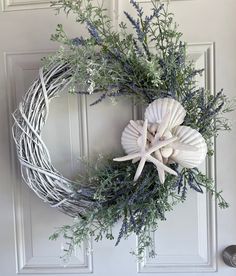 a wreath with sea shells and greenery on the front door