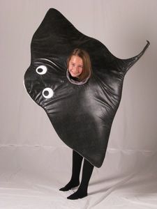 a woman in a black leather costume is holding up a large fish shaped object with eyes on it's back