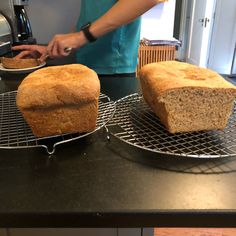 two loafs of bread sitting on top of cooling racks next to eachother