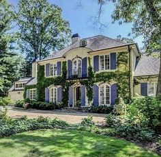 a large house with blue shutters and ivy growing on it's side yard