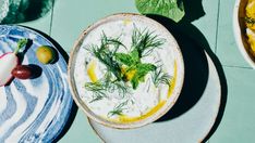 two plates with different foods on them and one bowl filled with dip, the other topped with dill