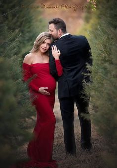 a pregnant woman in a red dress standing next to a man