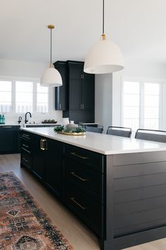 a large kitchen with black cabinets and white counter tops, along with an area rug on the floor