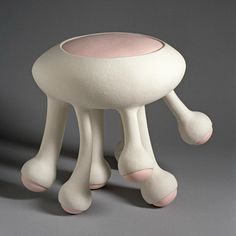 a white and pink stool sitting on top of a gray floor