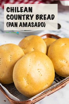 four bread rolls sitting in a basket on top of a table with a sign that says chilean country bread pan amasado