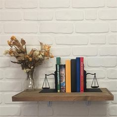 two books are sitting on a shelf next to a vase with flowers and a scale