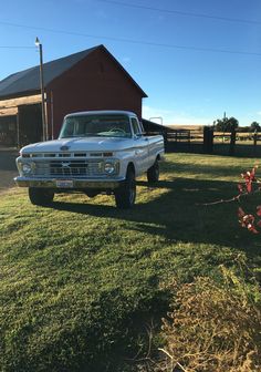 an old pickup truck parked in front of a barn