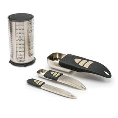 three knives and a measuring cup on a white surface