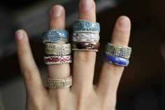 a person's hand with five different rings on it, all in different colors