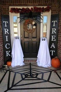 two halloween decorations on the front door of a house with ghost faces and eyes painted on them