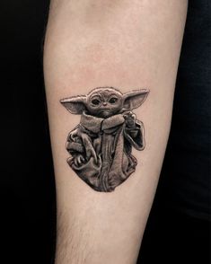 a black and white photo of a baby yoda tattoo