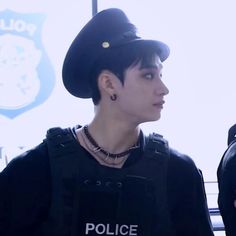 a young man wearing a police shirt and hat in front of a sign that says police