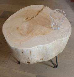 a glass sitting on top of a wooden table next to a metal leg rest and wood slice