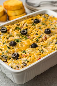 an enchilada casserole with olives and cheese in a white dish