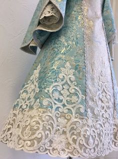 an ornate blue and white dress hanging on a wall