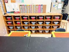 an empty classroom with desks and shelves filled with plastic containers, bookshelves, and other school supplies