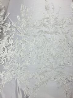 the white fabric has been embroidered on with beading and sequins in it