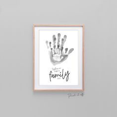 a hand print with the words family on it in a wooden frame against a gray wall