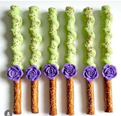 four sticks with flowers and sprinkles are arranged in the shape of roses