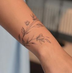 a woman's arm with a small flower tattoo on the left side of her arm