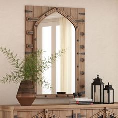 a mirror sitting on top of a wooden dresser next to a vase with a plant