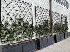 three black planters on the side of a white brick building