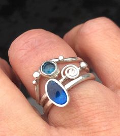 This Sterling Silver stack ring features  a London Blue Topaz stone and enamel. The approximate: 8mm wide ring is made of three seaside inspired rings and you can wear them any order, you wish. The first ring has a seashell and fine silver flat bubble detail. The 2nd is a blue enamelled pebble shaped ring and the 3rd is a wavy ring with a approx: 4mm wide London blue topaz and flat topped, bubble detail. Please let me know the ring size you need at Checkout and also whether you used a narrow rin Sterling Silver Rings Blue, Silver Ring Blue Stone, Silver Rings With Blue Stones, Vintage Blue Sterling Silver Rings, Handmade Silver Topaz Ring, Ring Inspo Jewelry, Silver Blue Jewelry, Silver Ring Stack, Wavy Ring