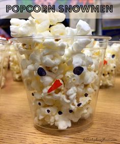 popcorn snowmen are sitting in plastic cups on a table with the words popcorn snowmen above them