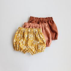 three pairs of bloomy shorts on a white background, one in orange and the other in pink