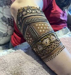 a woman is sitting on the bed with her arm covered in hendix and bracelets