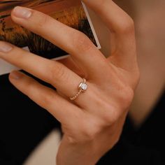 a woman's hand with a ring on her finger holding an open photo album