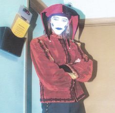 a mannequin wearing a red jacket and hat standing in front of a blue wall