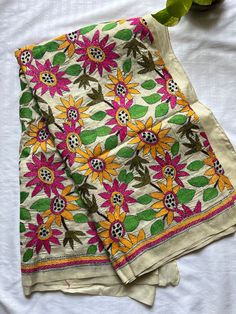 two napkins with flowers on them sitting on a white surface next to a green plant