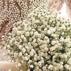 a bouquet of white flowers sitting on top of a table next to a vase filled with baby's breath