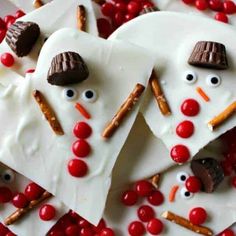 some white heart shaped treats are decorated like snowmen and reindeer noses with candy on them